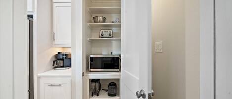 A kitchen with white cabinets, a coffee maker, a microwave, and a toaster.