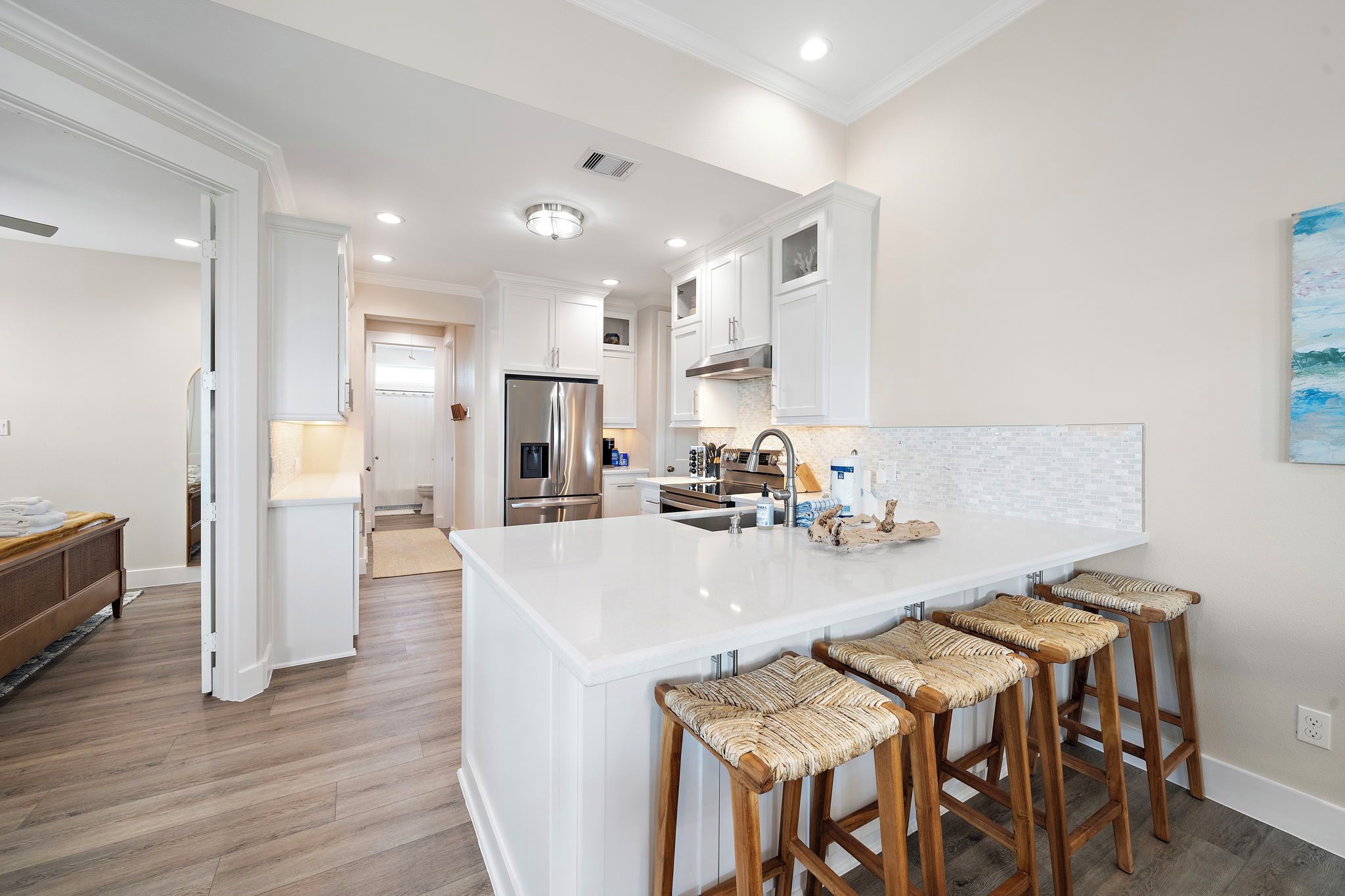A modern kitchen with a central island, bar stools, and a view into the dining area.