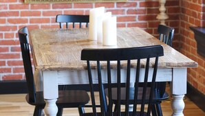 A rustic dining table with whitewashed wood, black chairs, and white candles. - Luxury Downtown Loft w/ Panoramic Views & (Baker City)