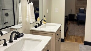 A bathroom with two sinks, a mirror, and a shower area. - Luxury Downtown Loft w/ Panoramic Views & (Baker City)