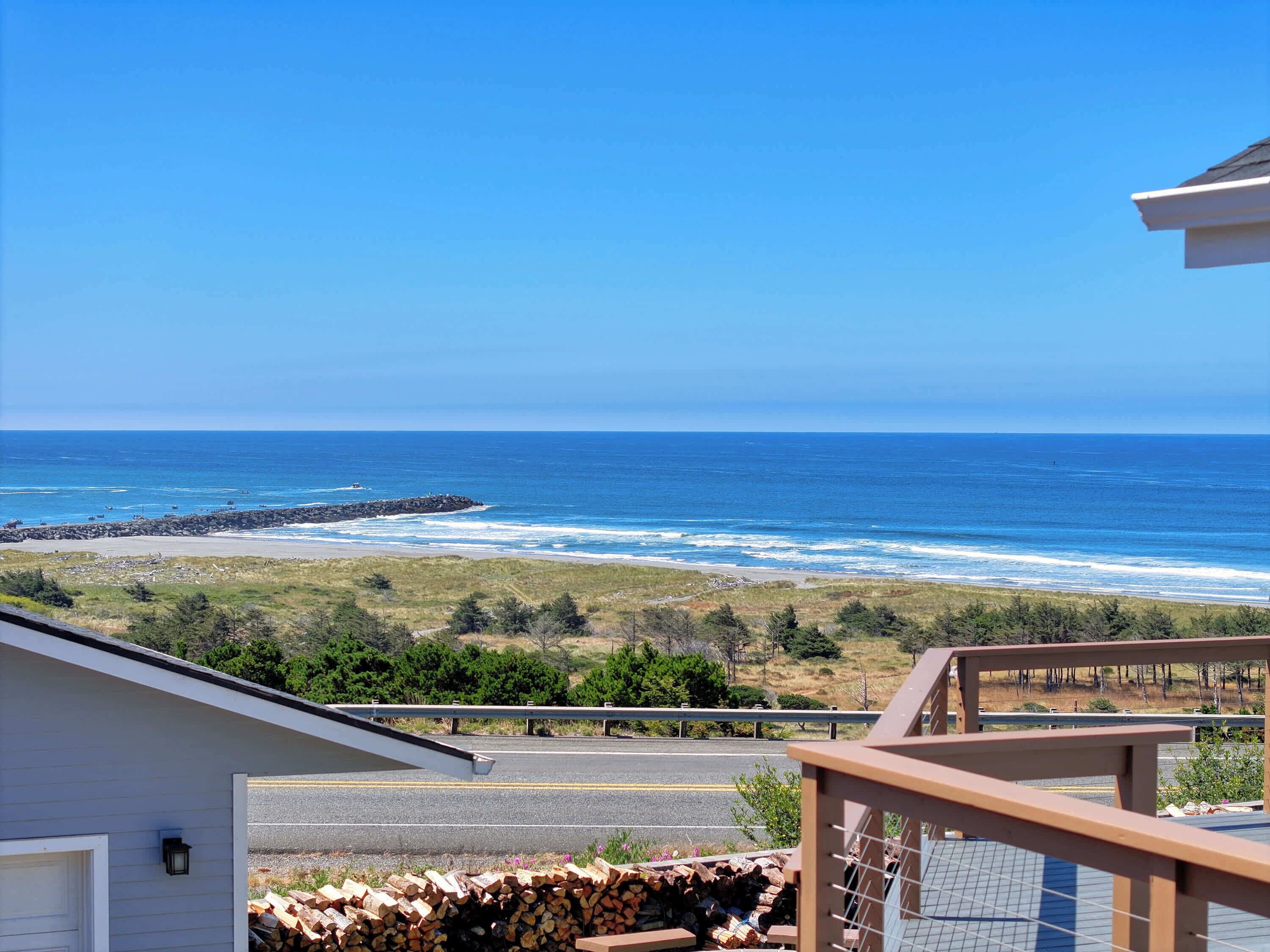 Vista costera con playa, océano y una carretera que lleva a una casa con balcón.