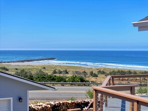 Eine Küstenansicht mit Strand, Meer und einer Straße, die zu einem Haus mit Balkon führt.