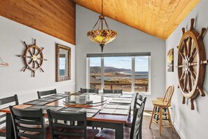 Un comedor con una mesa grande, sillas y vista al océano a través de un ventanal.