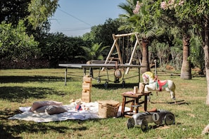A picnic setup with a table, a wooden structure, a horse-drawn carriage, and a blanket on the grass. - Ca´n Lull – Unique finca within olive grove, bespoke amenities (max. 10 guests) (Marratxi)
