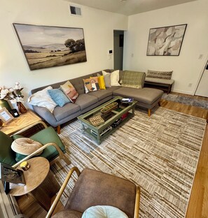 A modern living room with a sectional sofa, a coffee table, a green armchair, and a patterned rug. - 2BR/2BA in Andersonville · pet-friendly · workspace · garage parking · king beds (Chicago)