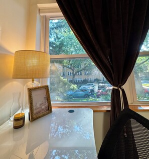 A room with a window, a lamp, a picture frame, and a candle on a table. - 2BR/2BA in Andersonville · pet-friendly · workspace · garage parking · king beds (Chicago)