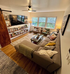 A cozy living room with a sofa, coffee table, and bookshelves. - 2BR/2BA in Andersonville · pet-friendly · workspace · garage parking · king beds (Chicago)