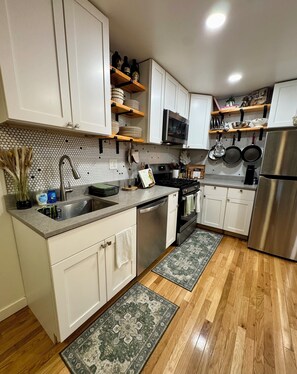 A modern kitchen with white cabinets, stainless steel appliances, and a herringbone tile backsplash. - 2BR/2BA in Andersonville · pet-friendly · workspace · garage parking · king beds (Chicago)