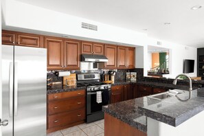 A modern kitchen with wooden cabinets, stainless steel appliances, and a granite countertop. - Designer Home • Free Heated Pool • BBQ • Game Room • Garage • Sleeps 16 (Gilbert)
