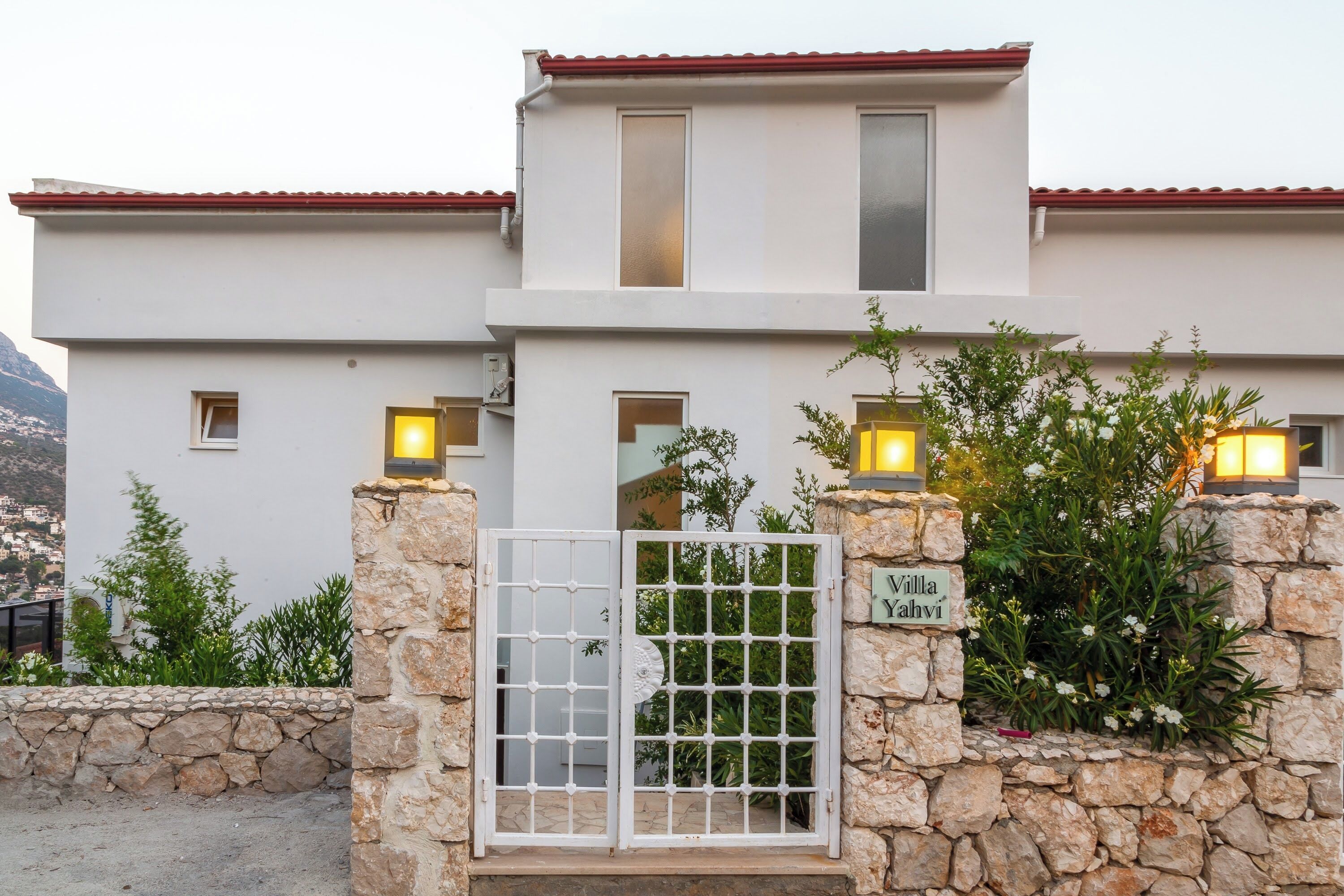 Una villa moderna con una puerta de piedra, una placa con el nombre y vistas del entorno.