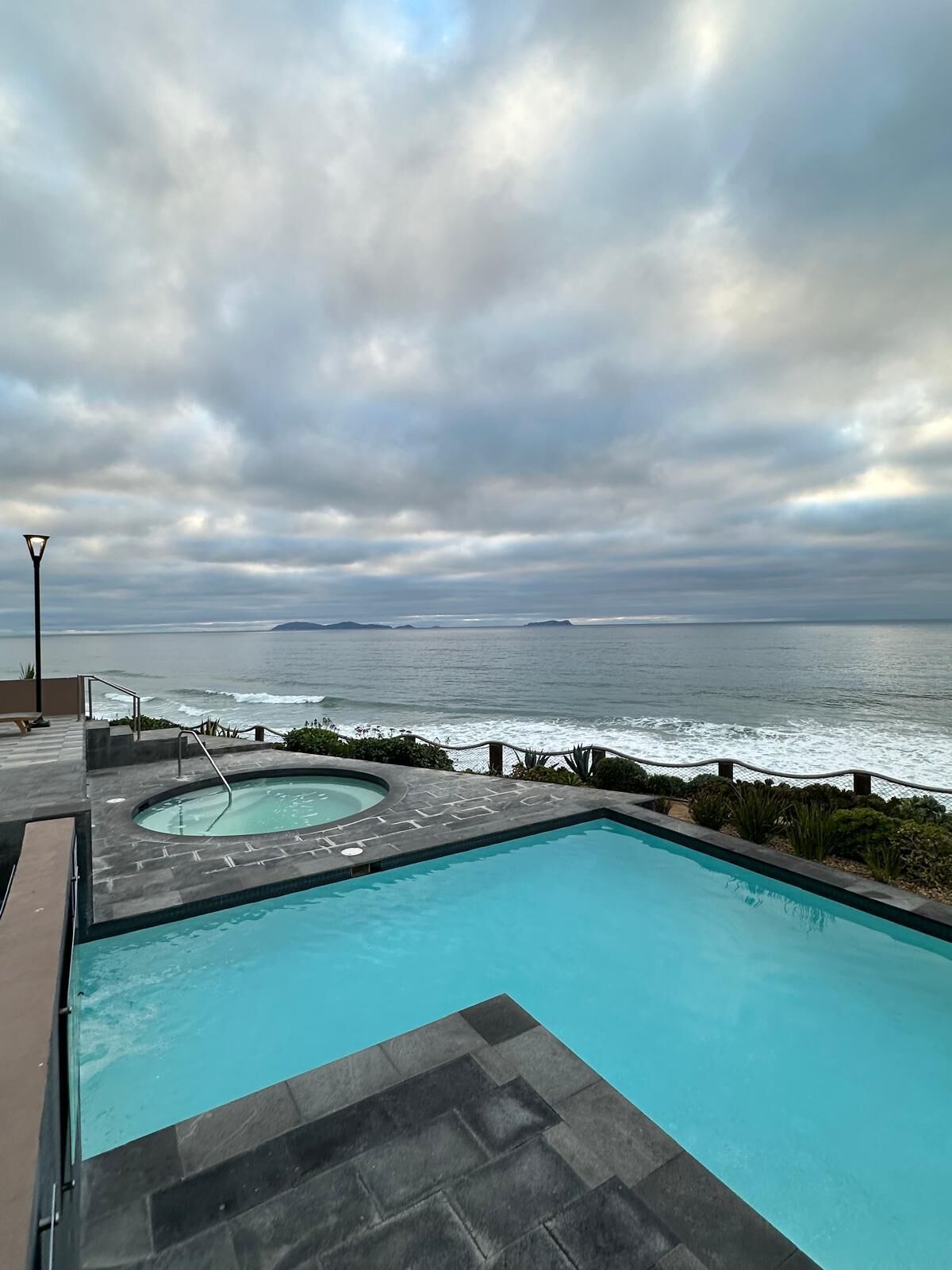 Ein Swimmingpool mit Blick auf den Ozean und einem bewölkten Himmel.