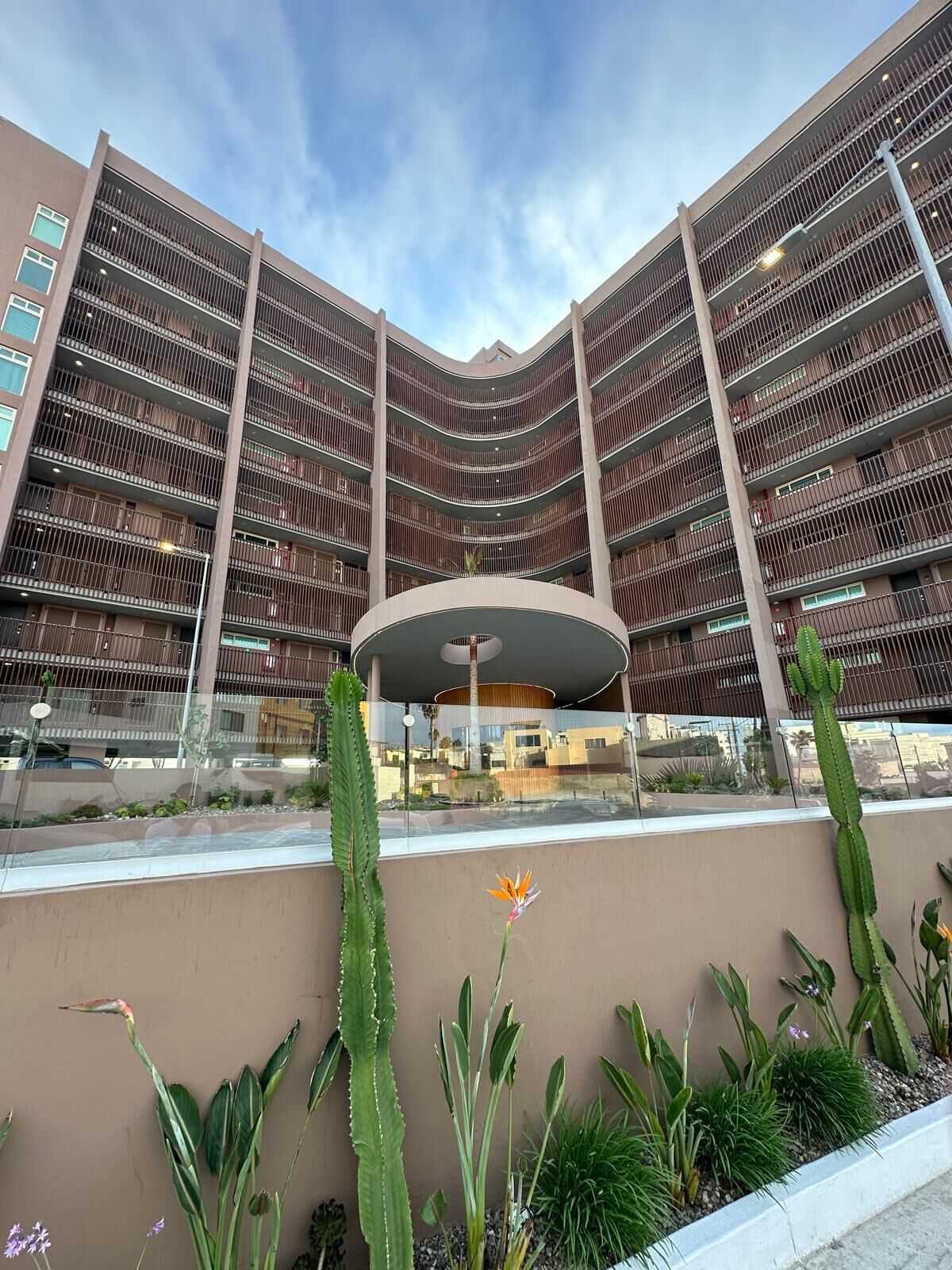 A multi-story building with a central atrium, surrounded by a variety of plants and cacti.
