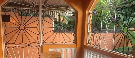 A room with a tiled floor, a table with a vase of sunflowers, two chairs, and a decorative metal gate.