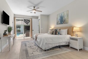 Ein Schlafzimmer mit einem Bett, Nachttischen, einem Deckenventilator, einem Fernseher und einem Gemälde an der Wand.