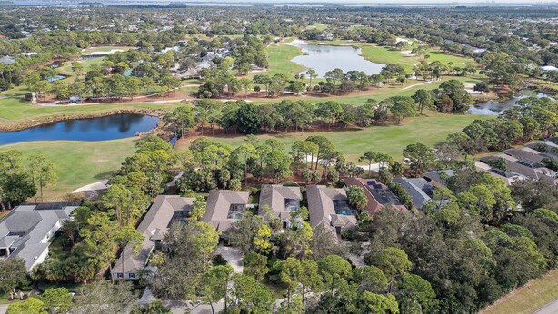 Vue aérienne d’un quartier résidentiel avec des maisons, un terrain de golf et un lac.