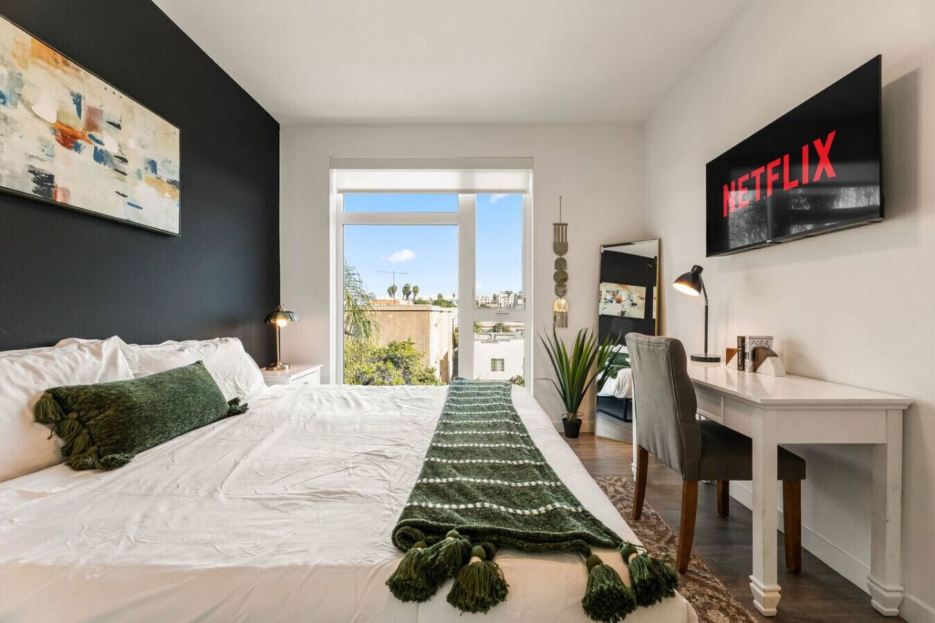 Une chambre moderne avec un grand lit, un bureau, une télévision et une vue sur la ville.