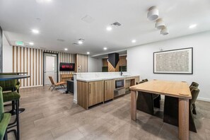 Une cuisine moderne avec un îlot central en bois, un coin repas doté d’une grande table et un espace détente avec des chaises.
