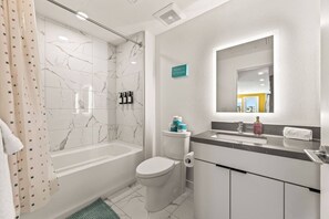 A modern bathroom with a bathtub, toilet, and sink. - Bright & Chic 2BDR Suite K-Town Haven, Hot tub + Gym (Los Angeles)