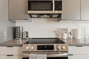 Une cuisine moderne équipée d’un four à micro-ondes, d’un four traditionnel et d’une plaque de cuisson intégrés.