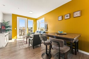 A modern living room with a dining area, large windows, and a view of the city. - Bright & Chic 2BDR Suite K-Town Haven, Hot tub + Gym (Los Angeles)