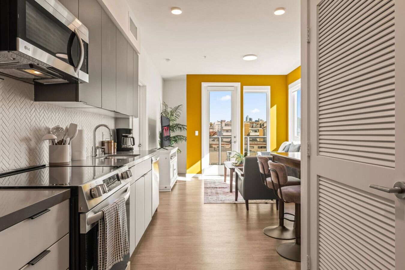 Une cuisine moderne équipée d’un four à micro-ondes, d’une cuisinière et d’un évier. On y trouve également un coin repas avec une table et des chaises. La pièce offre une vue sur la ville.