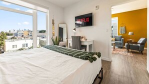 Une chambre d’hôtel avec un lit, un bureau, une chaise, une télévision et une vue sur la ville.