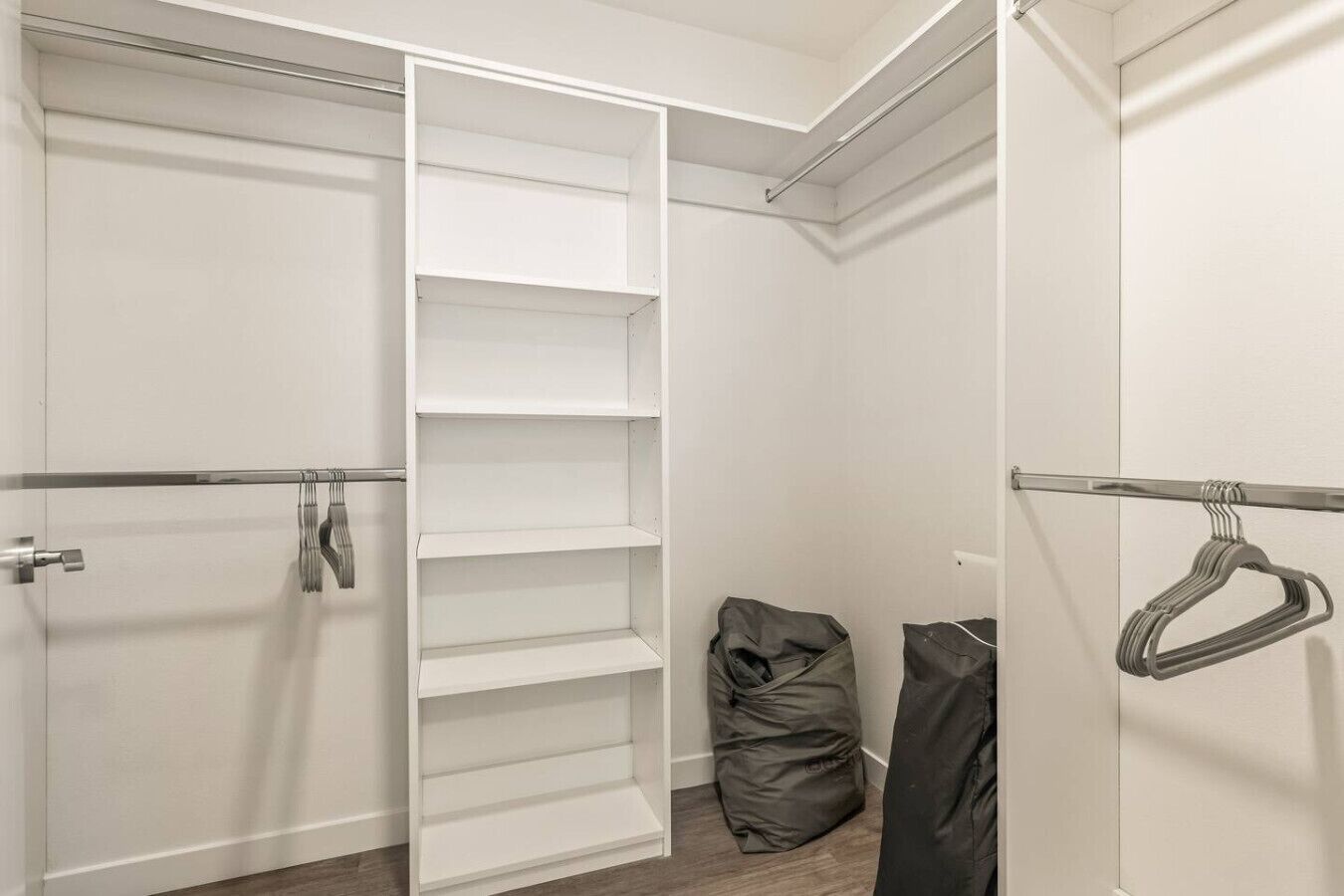 Un dressing avec des portes ouvertes, des étagères et une tringle pour suspendre les vêtements.
