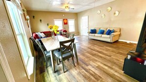 A dining area with a table and chairs, a sofa, a ceiling fan, and a fireplace.