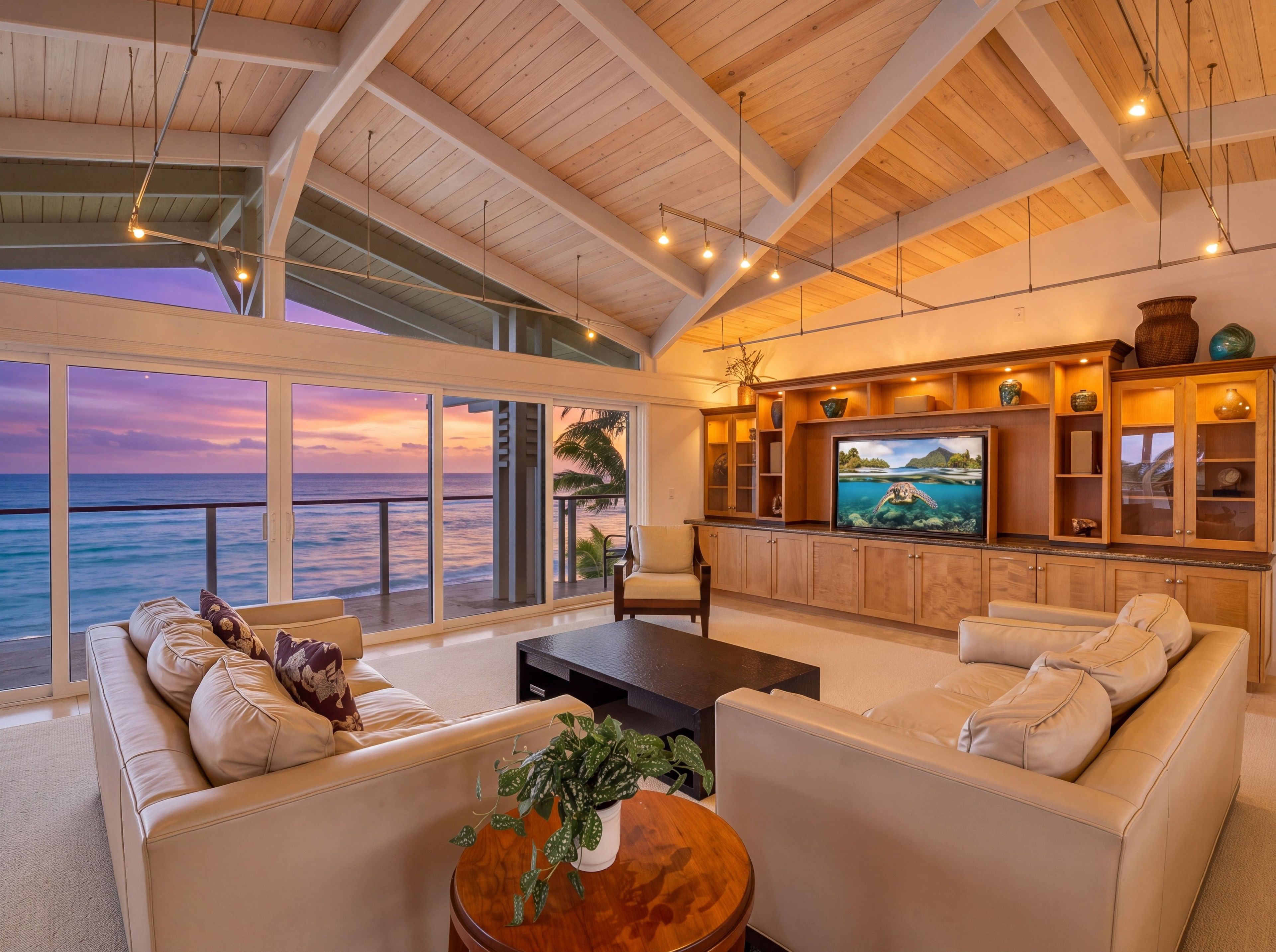 A spacious living area with a large television, comfortable seating, and a view of the ocean.