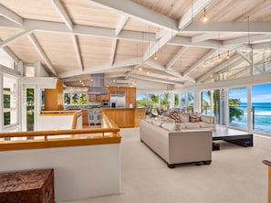A spacious living area with a large sofa, a dining table, and a kitchen area with modern appliances. - Beachfront North Shore Oahu Estate | Sunset Beach (Haleiwa)