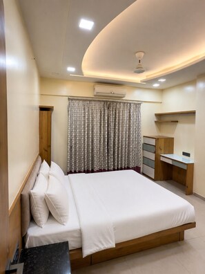 Un dormitorio con cama, escritorio, armario y aire acondicionado.