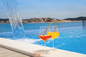 Two glasses of beverages on a poolside with a clear view of the water and a distant shoreline. - Luxury seaside Villa Porat with pool, sauna and sea view in Kanica-Rogoznica (Rogoznica)