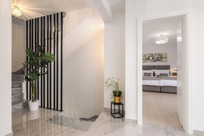 A modern interior with a staircase, a plant, a small table with an orchid, and a bedroom with a bed and a nightstand. - Luxury seaside Villa Porat with pool, sauna and sea view in Kanica-Rogoznica (Rogoznica)
