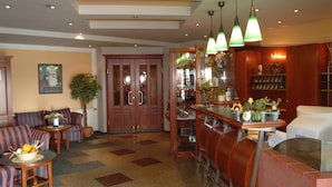 Rebedor d'hotel amb zona de bar, seients i una porta de fusta gran.
