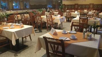 Ein Restaurant mit mehreren Tischen und Stühlen, manche mit Speisekarten, andere mit Tellern und Besteck.
