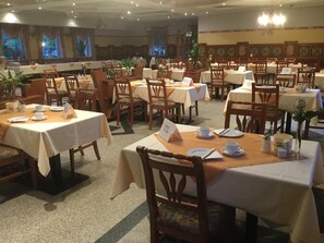 A restaurant with multiple tables and chairs, some with menus and others with plates and cutlery. - Radhotel Schischek (Halbenrain)