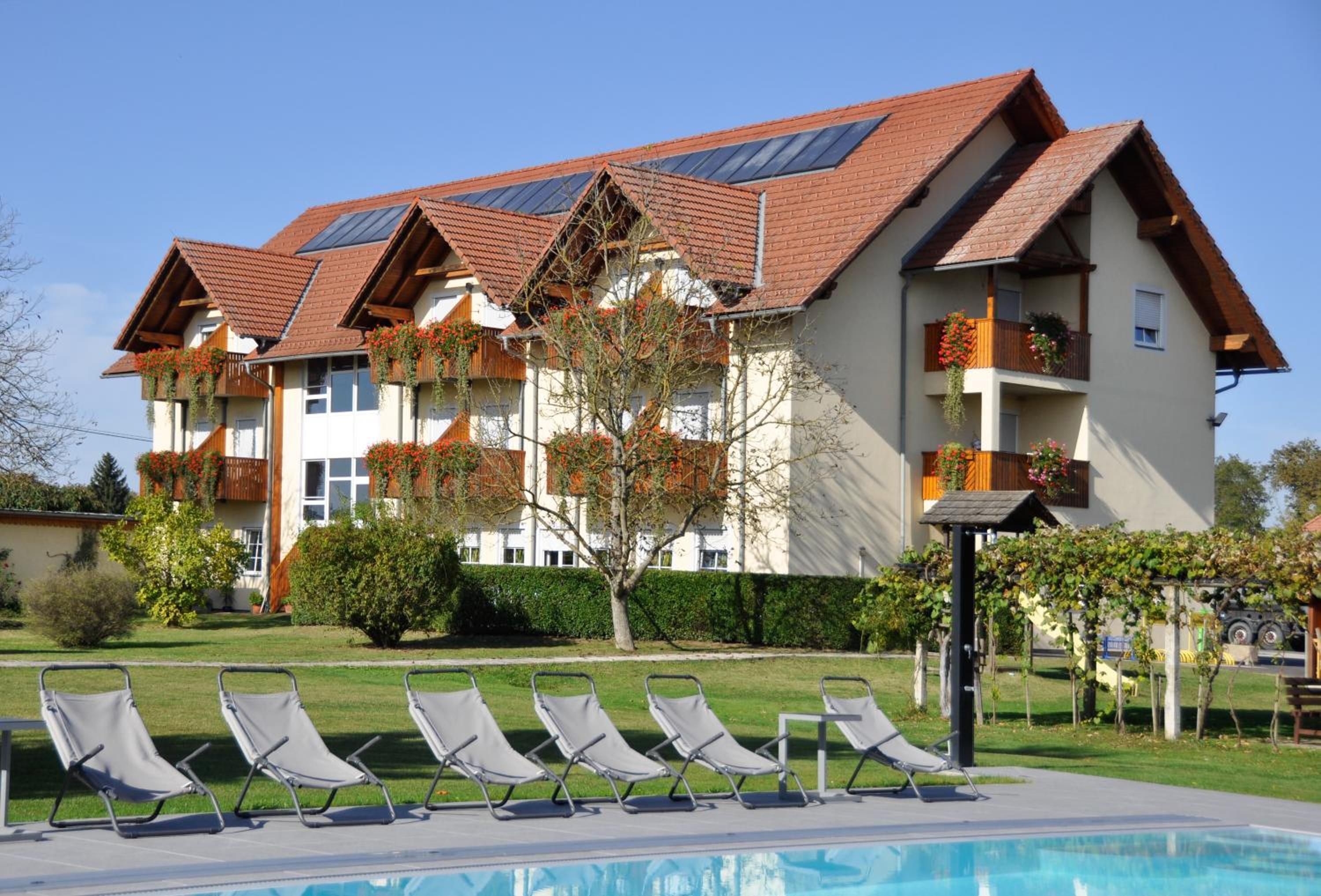 Un hôtel doté d’une piscine, de plusieurs balcons et d’un espace jardin aménagé avec des chaises longues.