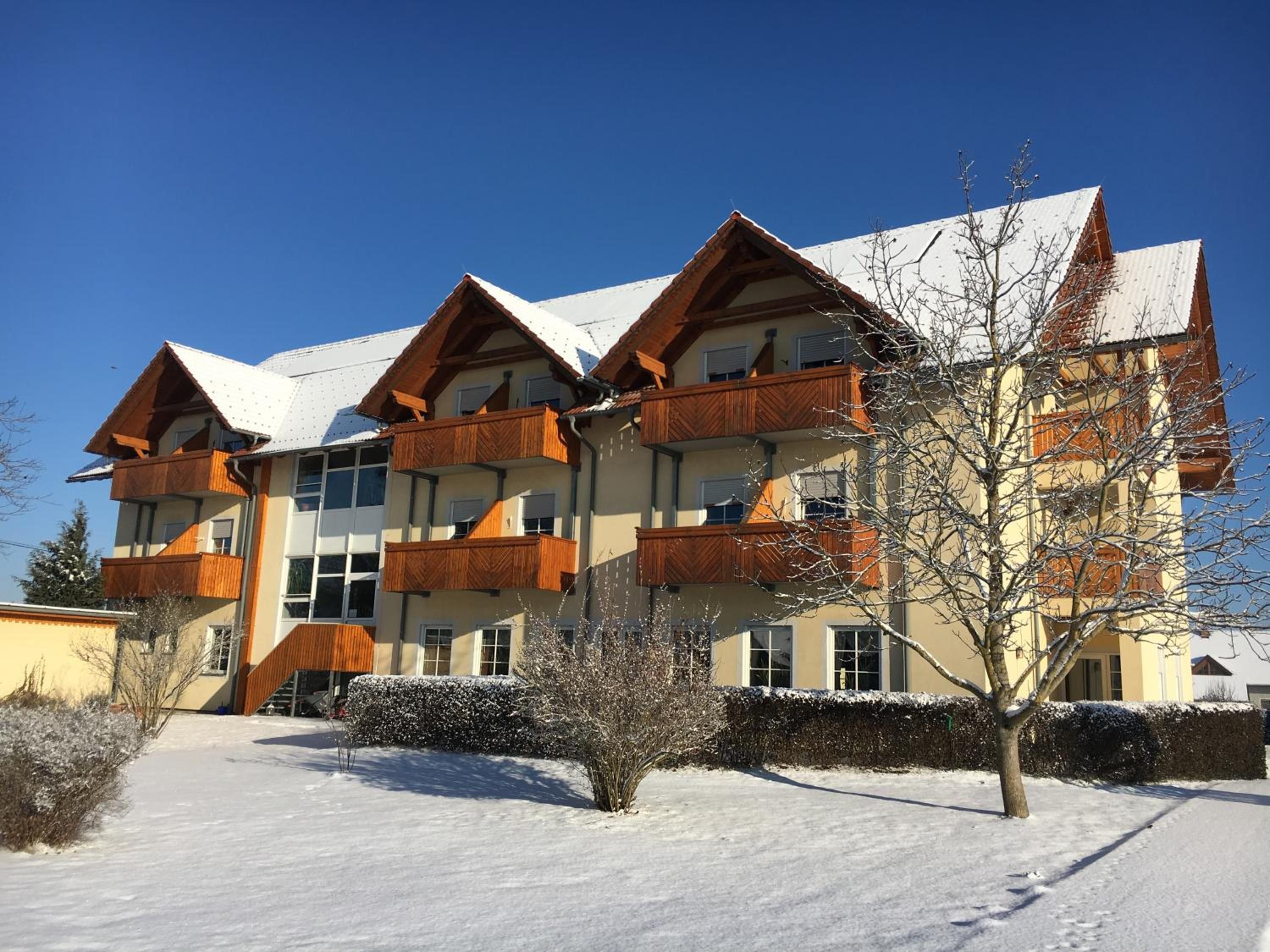 Un hôtel à plusieurs étages doté de balcons, entouré d’un paysage enneigé et surplombant un ciel dégagé.