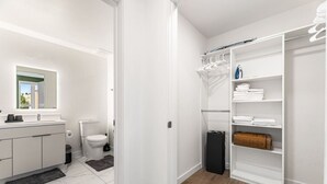 A modern bathroom with a toilet, sink, and a walk-in closet with shelves and hanging space. - Chic 2 room suite in K-Town, Free Parking, Hot tub + Gym (Los Angeles)
