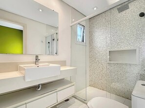 Un bagno moderno con lavandino bianco, specchio e zona doccia.