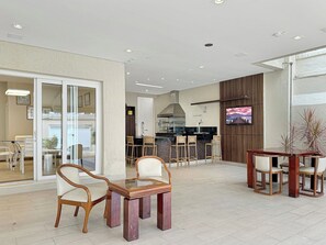 Un amplio espacio interior con comedor, zona de cocina y televisor montado en la pared.