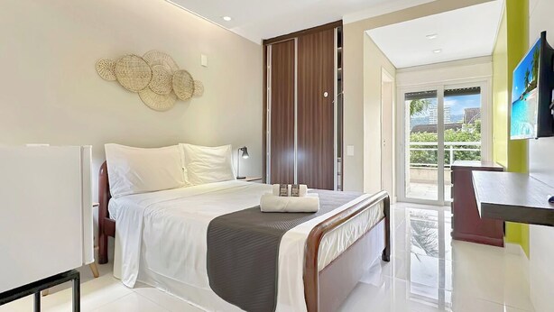 Quarto de hotel moderno com cama, mesa de cabeceira e vista para o exterior.