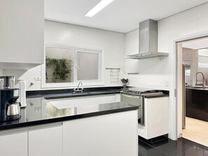Una cocina moderna con armarios blancos, encimera negra y electrodomésticos de acero inoxidable.