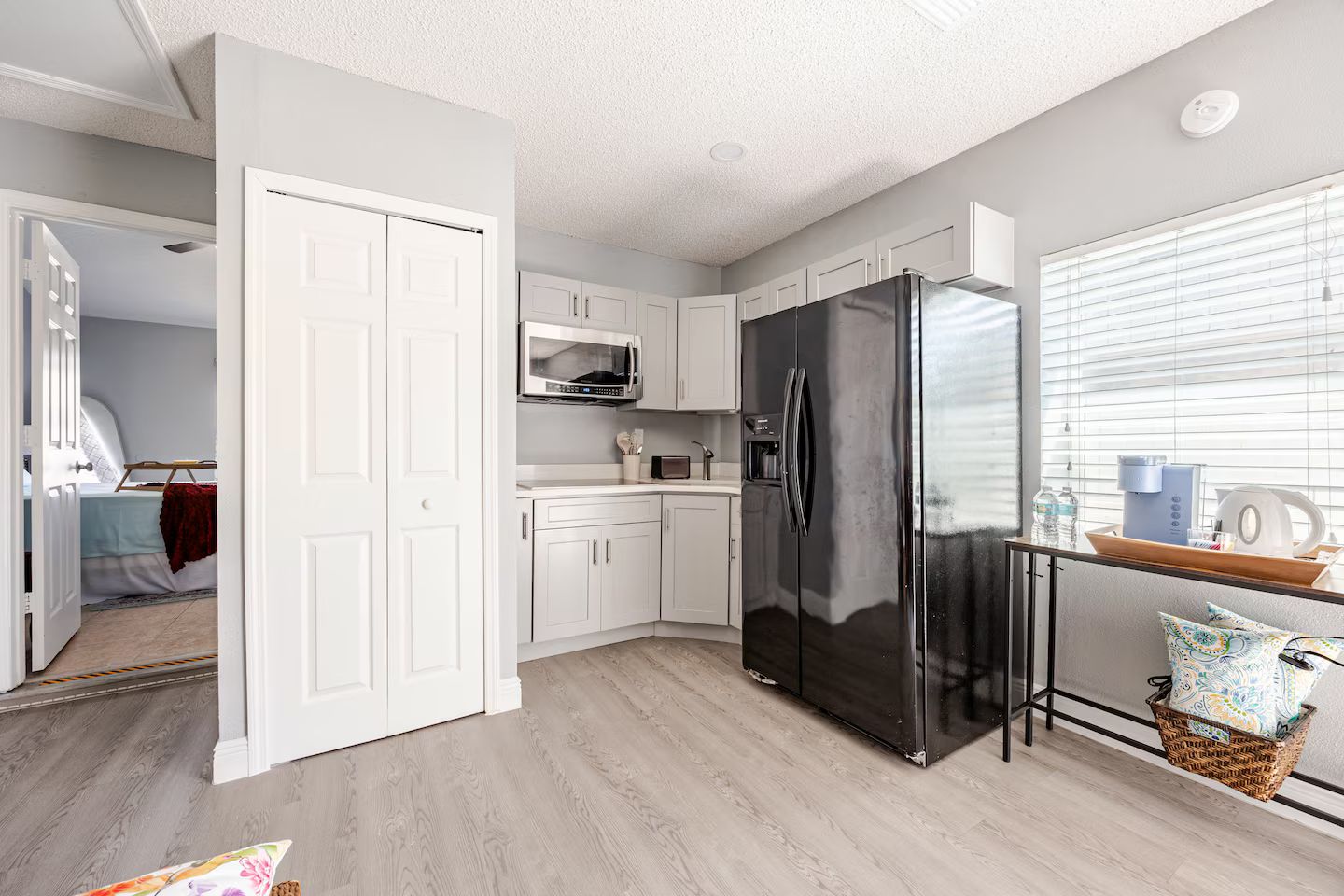 A modern kitchen with white cabinetry, a black refrigerator, and a microwave.