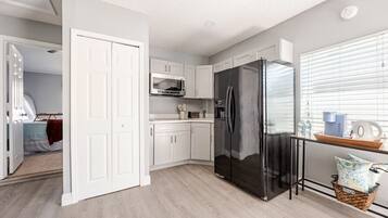 A modern kitchen with white cabinetry, a black refrigerator, and a microwave.