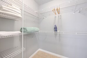 A laundry area with multiple shelves for folded clothes, a hanging rack, and an iron.