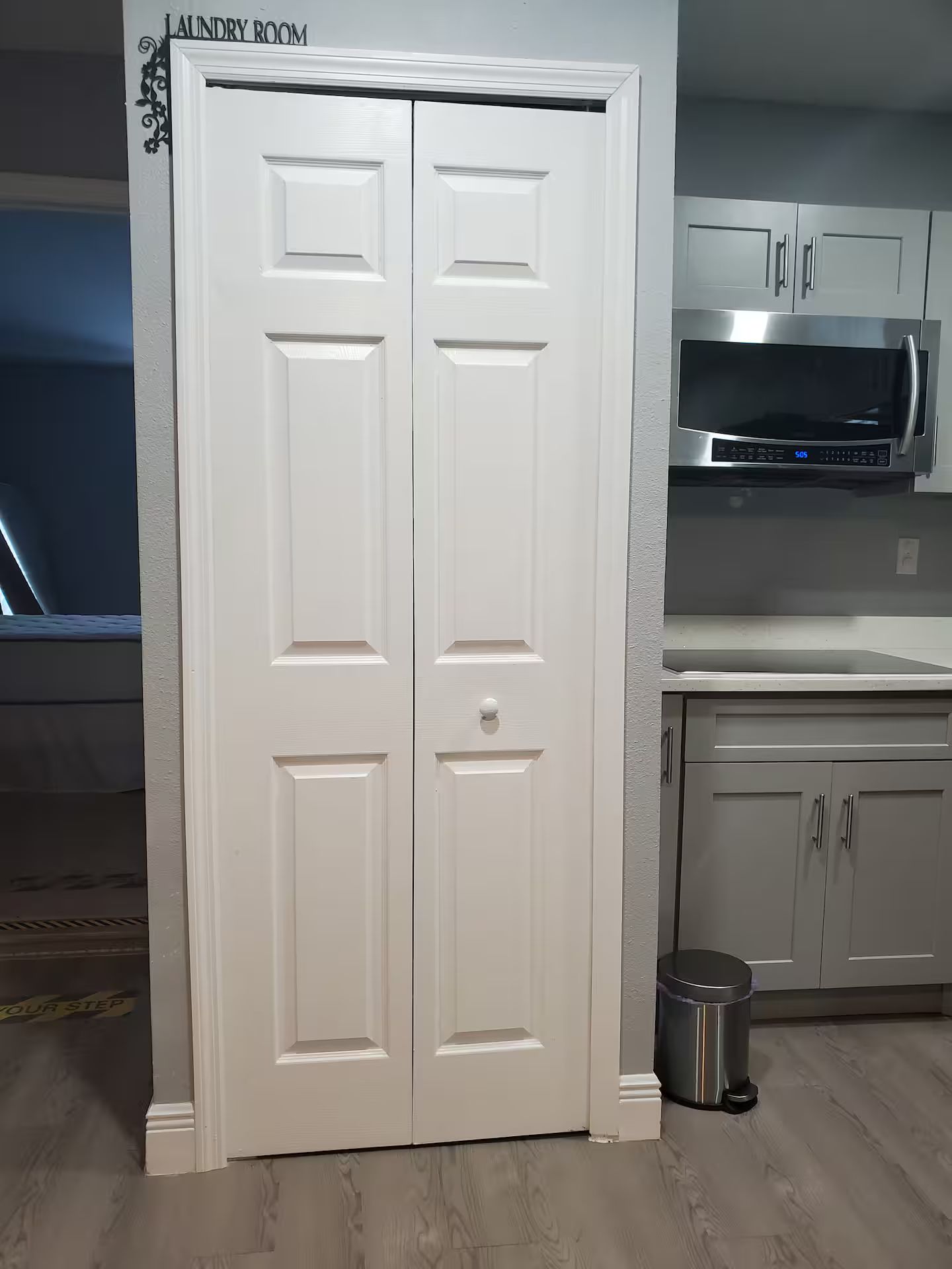 A laundry room with a double door, a microwave, and a trash can.