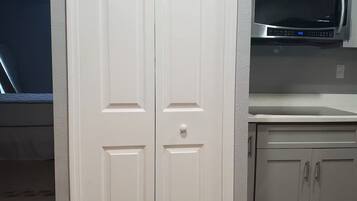 A laundry room with a double door, a microwave, and a trash can.
