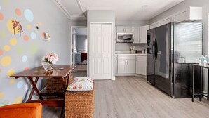 A modern kitchen with white cabinets, a stainless steel refrigerator, and a microwave.