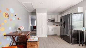 A modern kitchen with white cabinets, a stainless steel refrigerator, and a microwave.
